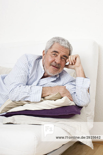 Ein älterer Mann  der auf einer Couch liegt.