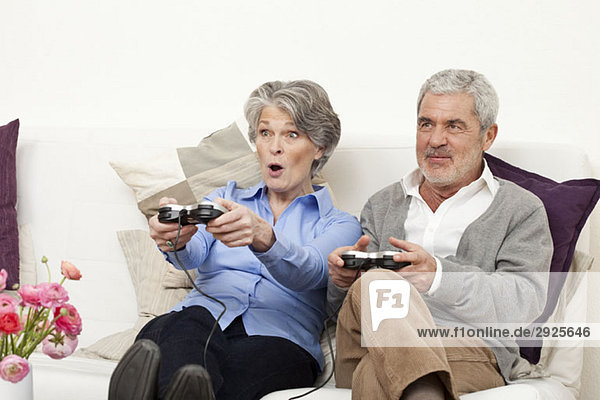 Ein älterer Mann und eine ältere Frau spielen ein Videospiel.