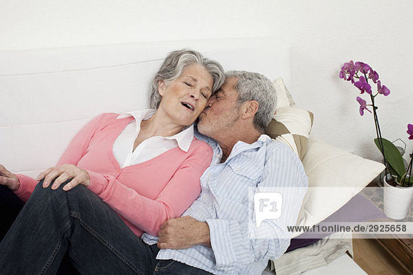 A senior man and senior woman lying on a couch together