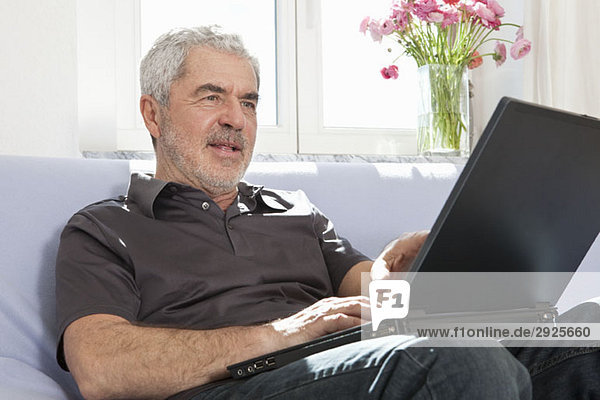 Ein älterer Mann  der einen Laptop benutzt.