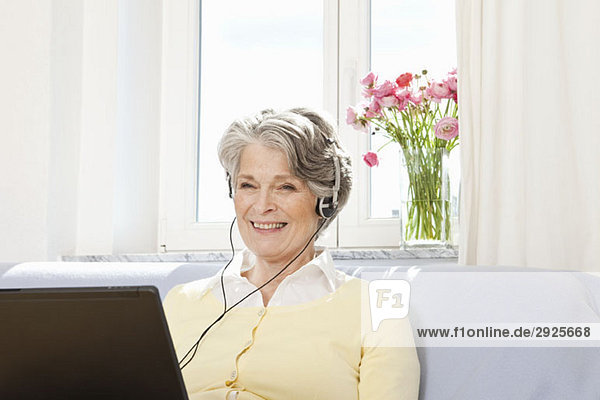 A woman using a laptop and listening to headphones