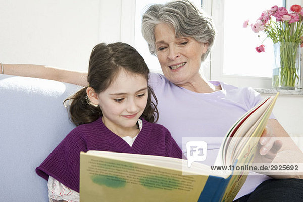 Eine Großmutter liest mit ihrer Enkelin ein Buch.