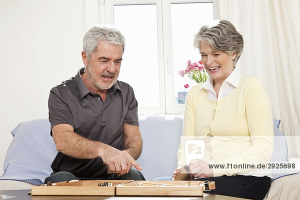 A senior man and a senior woman playing backgammon