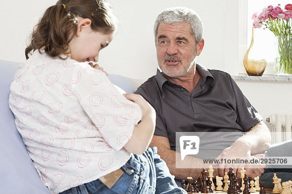 Ein Großvater und seine Enkelin spielen Schach.