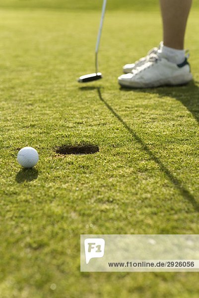 Detail eines Golfballs neben einem Loch