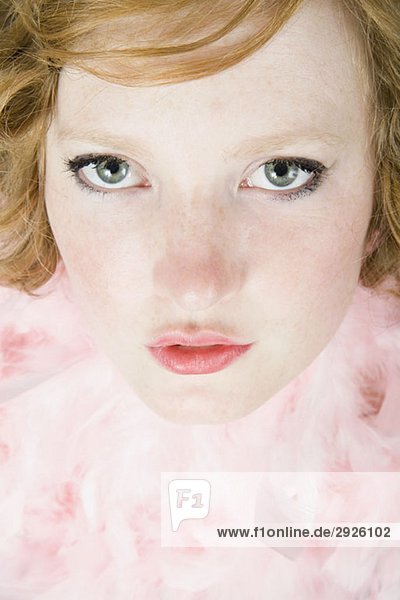 Ein Porträt einer jungen Frau  die eine rosa Federboa trägt.