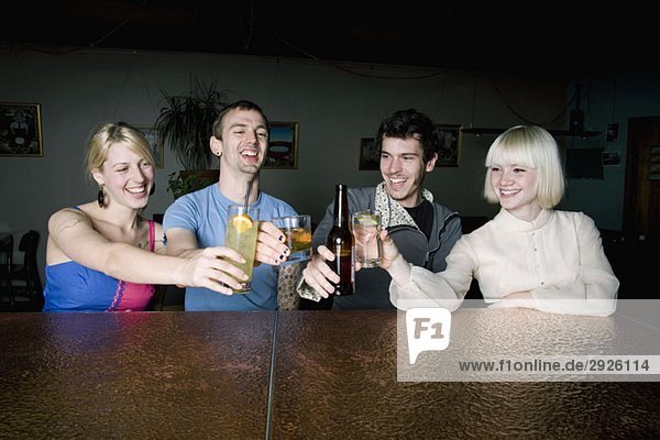 Vier Freunde stoßen an einer Bar auf einen Drink an.