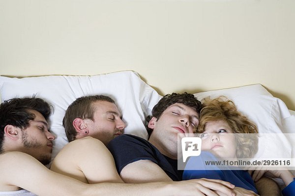 Vier Freunde  die zusammen in einem Bett liegen.