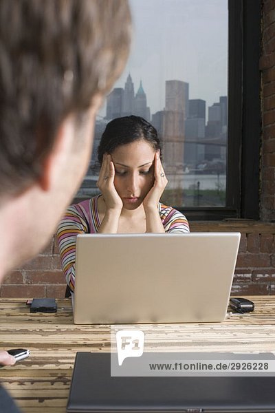 Frau sitzt am Laptop und sieht gestresst aus