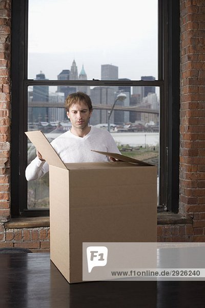 Mann beim Auspacken des Kartons im Büro