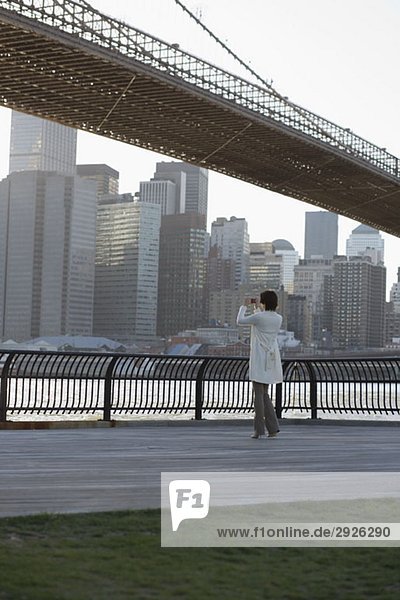 Eine Frau fotografiert in der Nähe der Brooklyn Bridge  New York City.