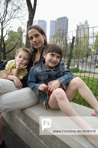 Eine Frau und ihre Kinder sitzen zusammen auf einer Parkbank  Central Park  New York City