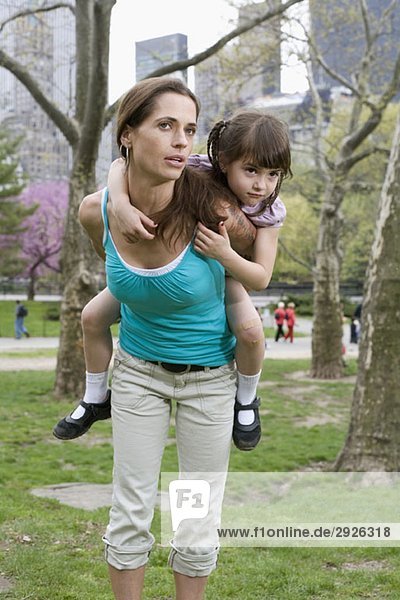 A woman carrying her daughter on her back  Central Park  New York City