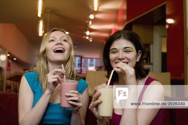 Two young women drinking fruit smoothies