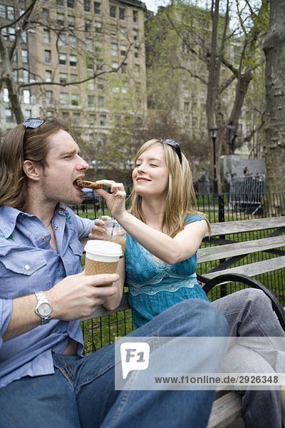 A woman feeding a man a cookie in a park  Central Park  New York City