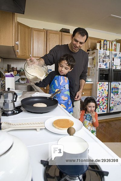 Ein Vater und seine Kinder machen zusammen Pfannkuchen.