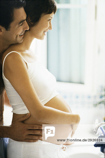 Paar mit den Händen auf dem schwangeren Bauch  Seitenansicht
