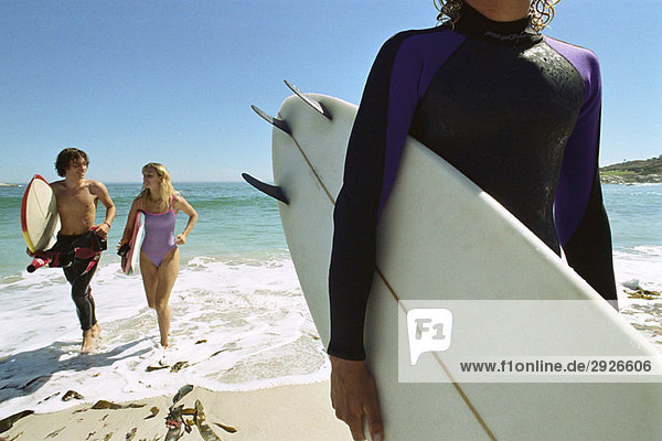 Surfer tragendes Brett unter dem Arm  Paar  das zusammen aus dem Wasser aufsteigt.