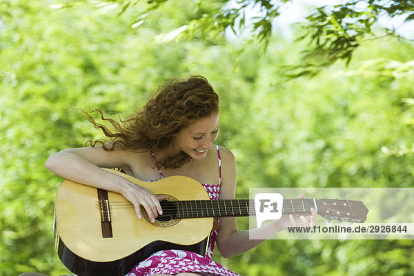 Junge Frau spielt Akustikgitarre im Freien