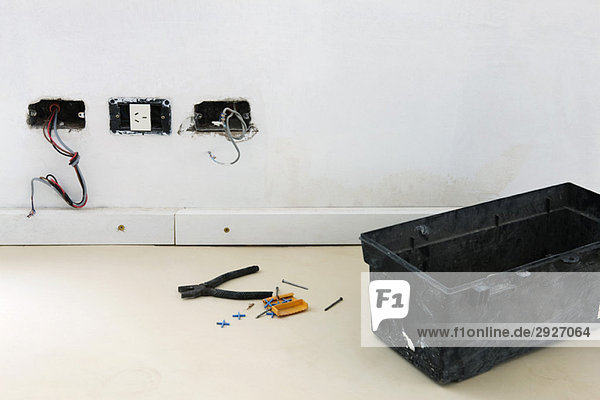 Kunststoff-Werkzeugkasten  Zange am Boden in der Nähe von unfertigen Steckdosen