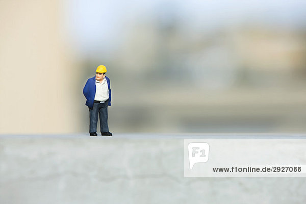 Plastikfigur des Bauarbeiters auf Sims gesetzt