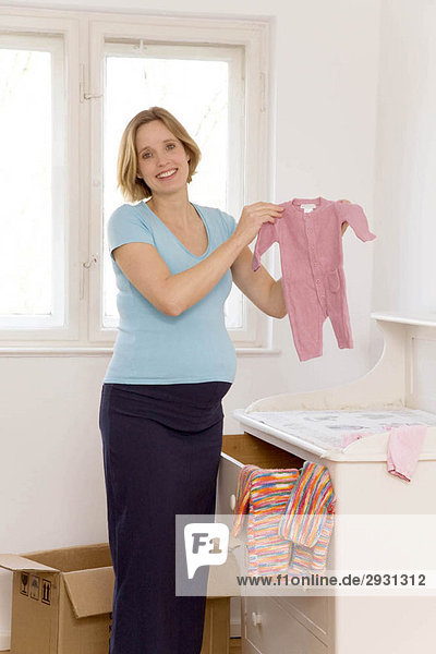 schwangere Frau bei der Auswahl der Babykleidung