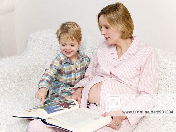 schwangere Frau und Junge lesen Buch