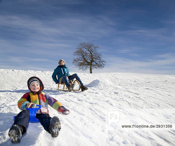 Junge und Mädchen beim Schlittenfahren im Schnee