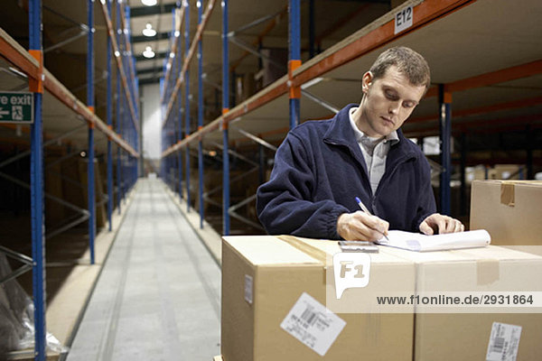 Worker filling in paperwork in warehouse