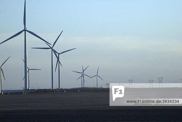 Farming equipment dwarfed by array of wind turbines