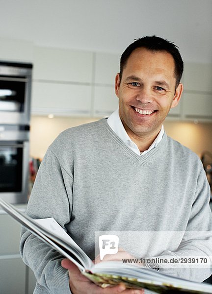 Ein lächelnd mann  der ein Kochbuch Schweden hält.