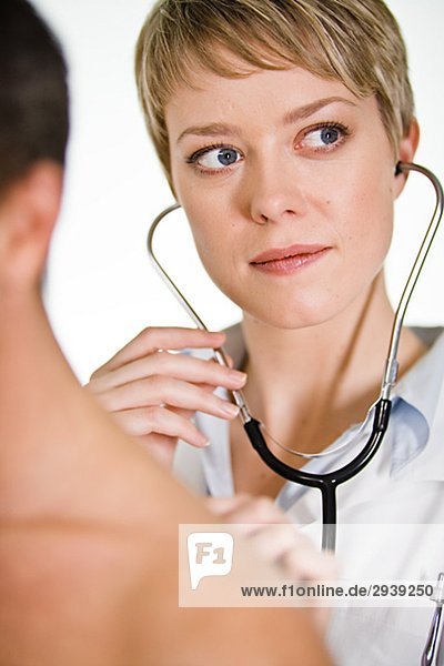 Ärztin mit ein Stethoskop bei einem männlichen Patienten Schweden.