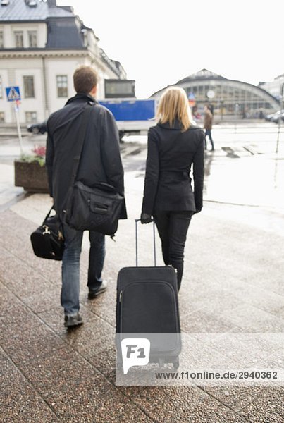 Mann und Frau von hinten mit Koffer