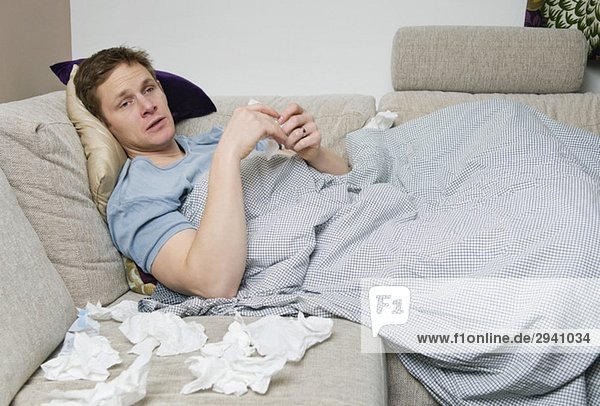 Man with cold lying on sofa