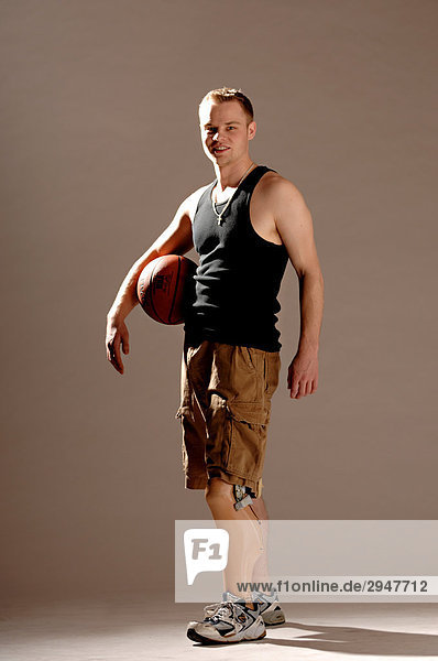 Junger Mann mit einer Prothese halten einen Basketball