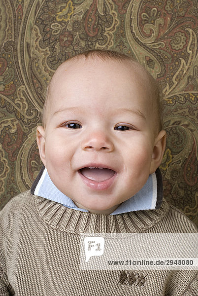 Portrait eines Babys lächelnd an einem gemusterten Hintergrund