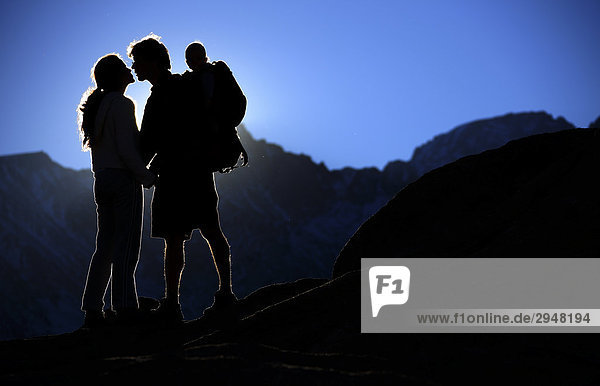 Junges paar küssen bei der Festlegung der Sonne während des Tragens Sohn auf Back  Sierra Nevada  Kalifornien