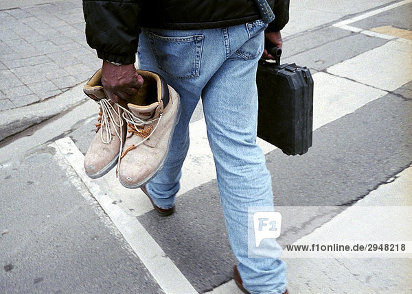 Mann überqueren einer Straße mit Tools und Arbeitsstiefel