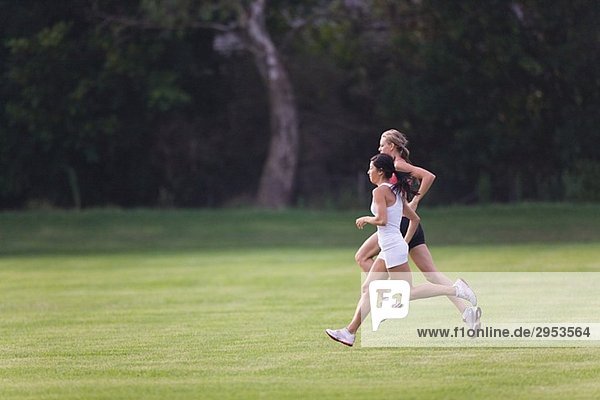 Two Women Running Together on Grass