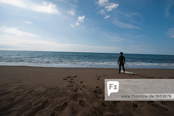 Junger Mann im Anzug stehen am Strand
