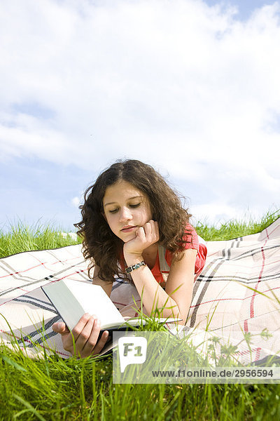 Junges Mädchen auf Decke liegend  ein Buch lesend  Flachwinkelansicht