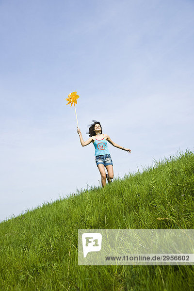 Girl playing with windmill on a meadow