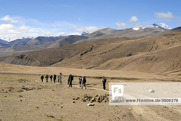 Trekking group hikes in wide open landscape Mt. Everest in the background Tibet China