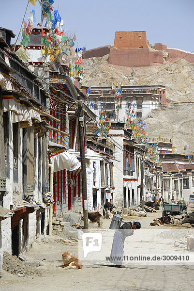 Street scene woman carries heavy bucket in old town Gyantse Tibet China