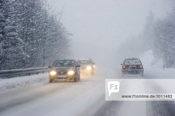Straßenverkehr im Winter bei Schneetreiben Landstraße Bayern Deutschland