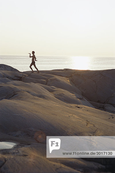 Silhouette of a person on a cliff in the sunset.