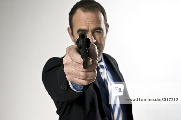 Headline: Businessman aiming a gun at camera  front view