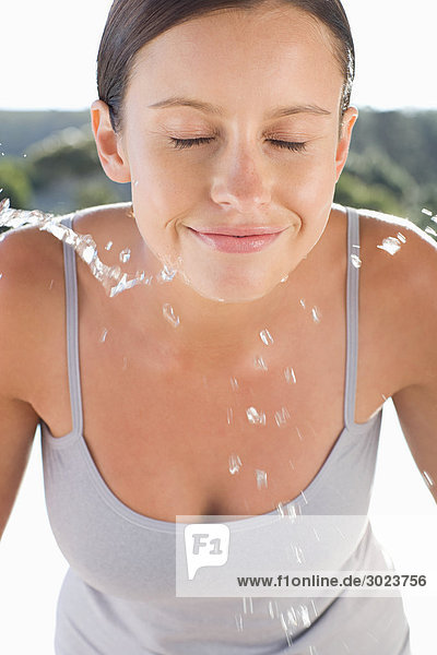 Junge Frau spritzt Wasser ins Gesicht
