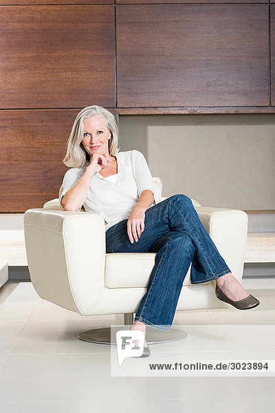 Portrait of middle aged woman sitting on modern armchair