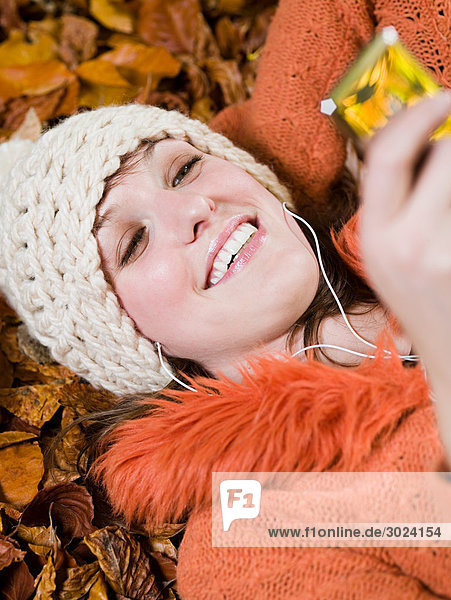 Frau hört Musik auf Herbstblättern